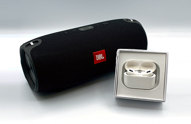 A JBL speaker and Airpods with a grey background.
